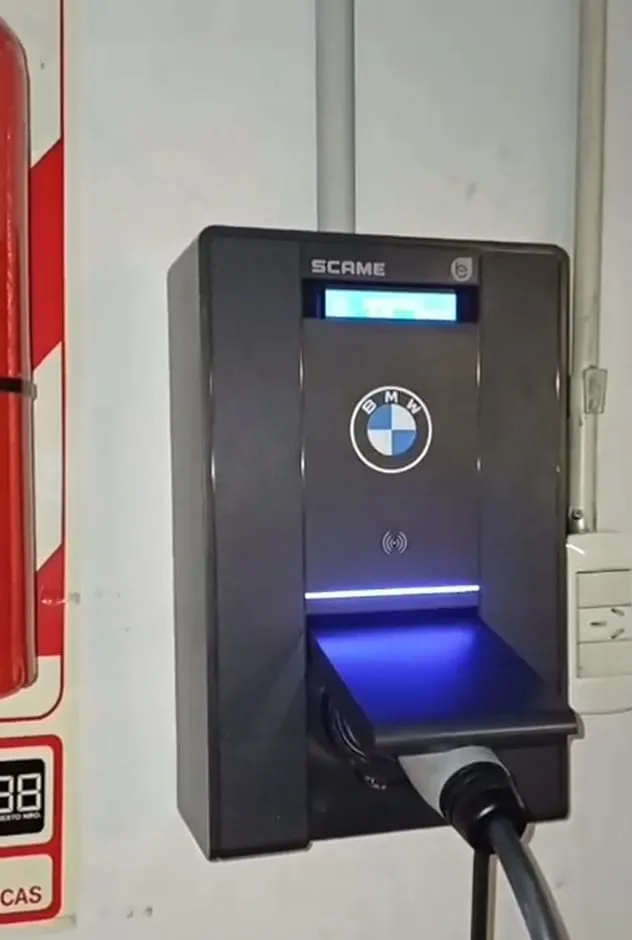 Cargador de auto eléctrico funcionando en la cochera de un edificio, con el conector enchufado