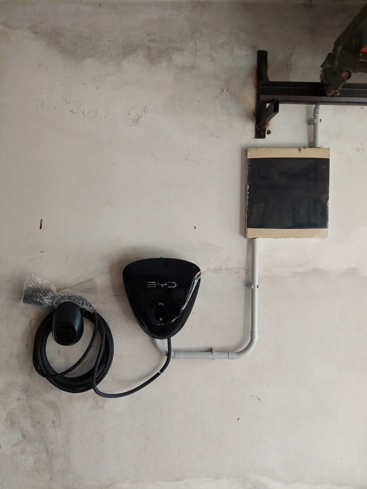 Cargador de auto eléctrico recién instalado junto a un tablero seccional, con cañería a la vista